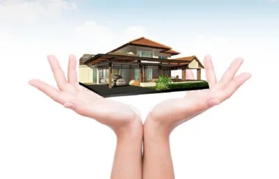 House in human hand over blue sky